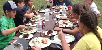 Kids eating catered food at a picnic table 