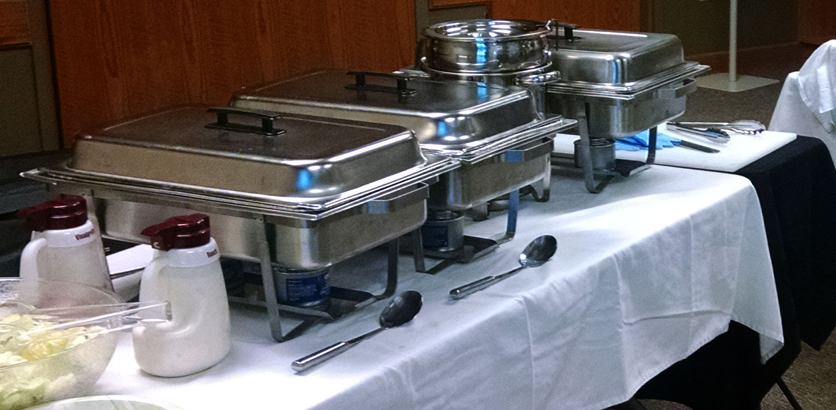 Business luncheon menu catered by Old West Dutch Oven Catering Company, showing chaffers, eating and serving utensils and professional table layout.